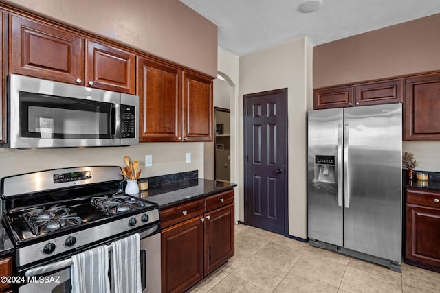 kitchen featuring dark stone countertops, appliances with stainless steel finishes, and light tile patterned flooring