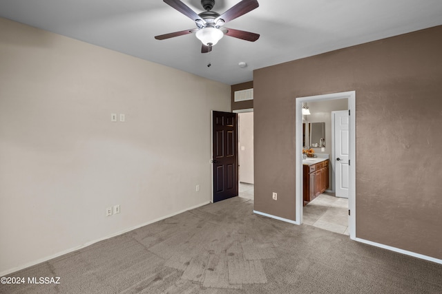 unfurnished bedroom featuring light colored carpet, ceiling fan, and ensuite bath