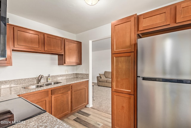 kitchen featuring light wood-type flooring, stainless steel refrigerator, and sink