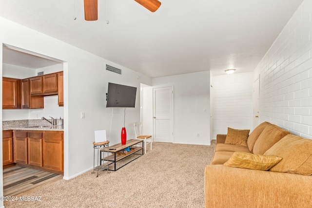 living room with light colored carpet, ceiling fan, and sink