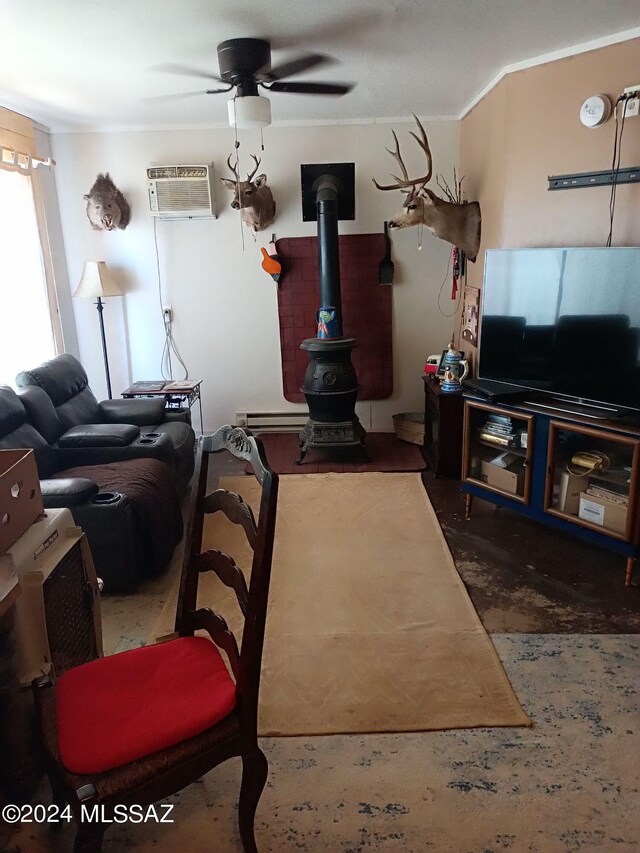 living room featuring a wall mounted AC, ornamental molding, a wood stove, ceiling fan, and a baseboard heating unit