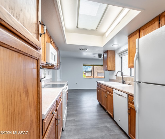 kitchen featuring ceiling fan, white appliances, dark hardwood / wood-style flooring, a raised ceiling, and sink