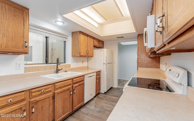 kitchen with light wood-type flooring, white appliances, and sink