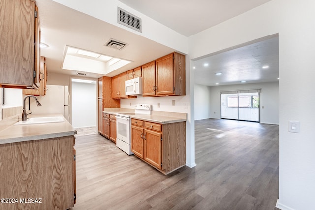 kitchen with a skylight, light wood-type flooring, sink, and white appliances