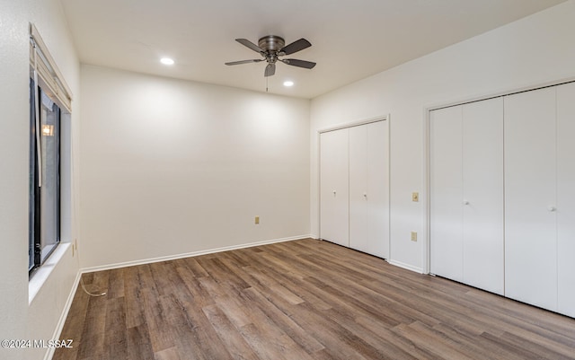 unfurnished bedroom with wood-type flooring, two closets, and ceiling fan