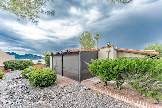 view of side of home featuring a sunroom and a mountain view