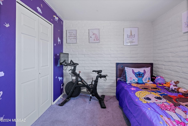 carpeted bedroom with brick wall and a closet