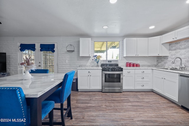 kitchen with white cabinets, appliances with stainless steel finishes, hardwood / wood-style floors, and sink