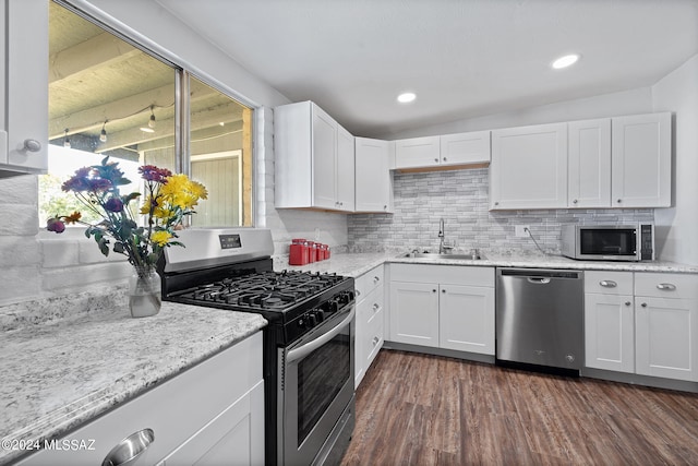 kitchen with dark wood-type flooring, stainless steel appliances, sink, decorative backsplash, and white cabinetry