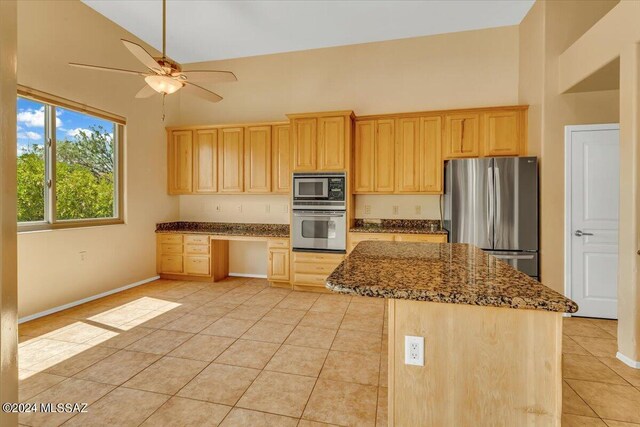 kitchen with appliances with stainless steel finishes, dark stone countertops, high vaulted ceiling, light tile patterned floors, and ceiling fan