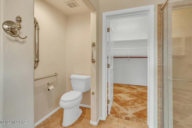 bathroom featuring a shower with door and toilet