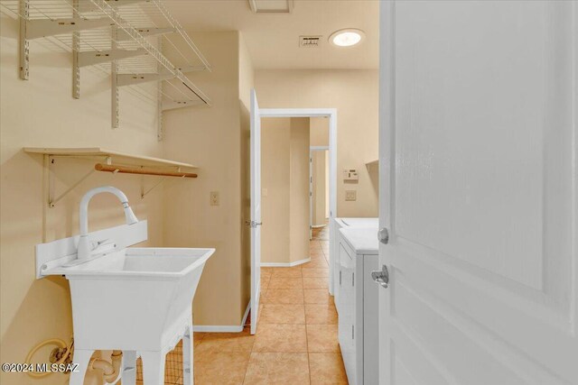 laundry area featuring washer and clothes dryer, sink, and light tile patterned floors