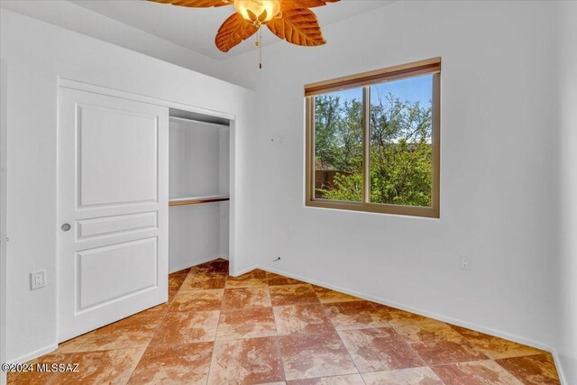 unfurnished bedroom with ceiling fan and a closet