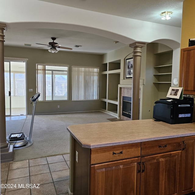 kitchen with light carpet, built in features, a ceiling fan, light countertops, and ornate columns