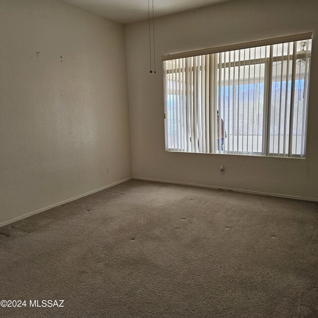 carpeted empty room with ceiling fan and plenty of natural light