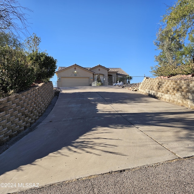 view of front of house with a tile roof, stucco siding, an attached garage, fence, and driveway