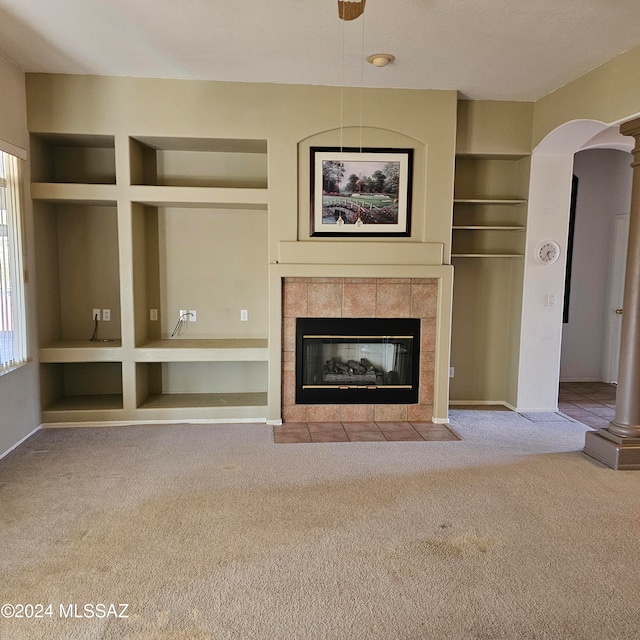 unfurnished living room featuring built in shelves, light colored carpet, and a tiled fireplace