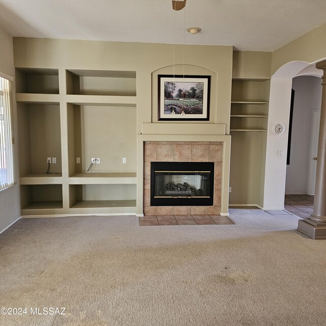 unfurnished living room with a tiled fireplace and carpet floors