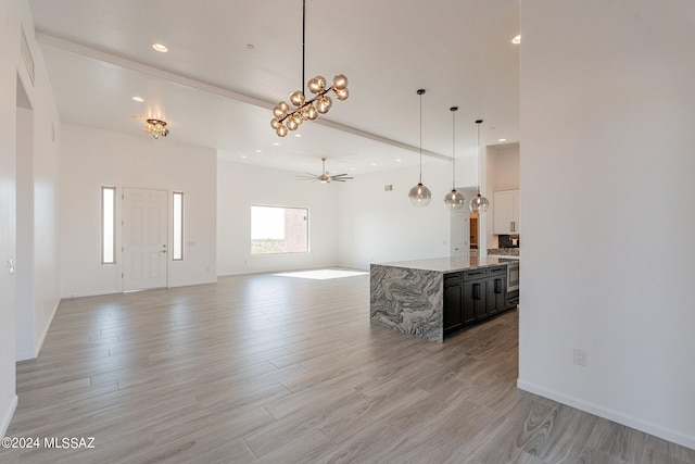 kitchen featuring light stone countertops, ceiling fan with notable chandelier, decorative light fixtures, and light hardwood / wood-style floors