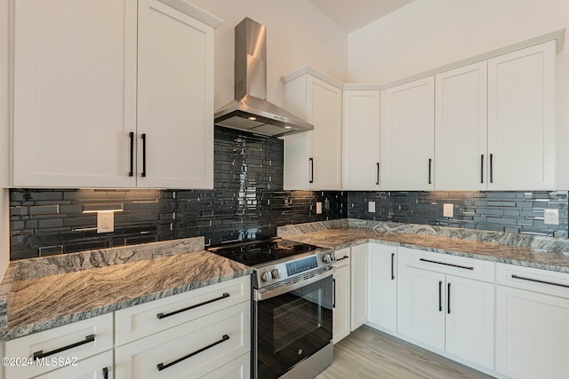 kitchen with stainless steel electric range oven, wall chimney exhaust hood, white cabinetry, and tasteful backsplash