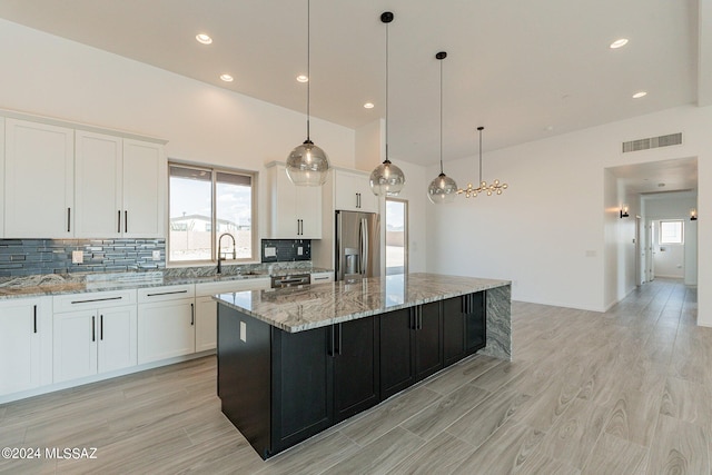 kitchen with appliances with stainless steel finishes, white cabinetry, a center island, and pendant lighting