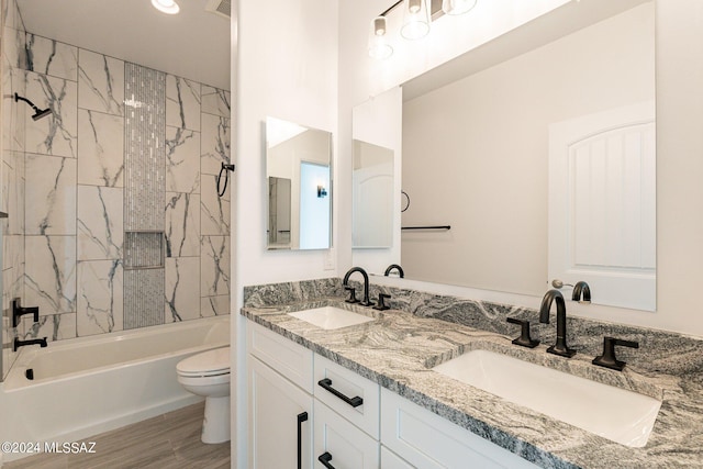 full bathroom featuring wood-type flooring, toilet, tiled shower / bath, and vanity