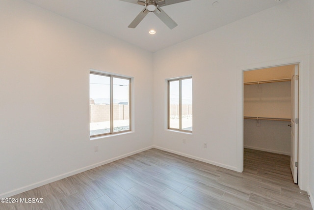 unfurnished bedroom with light hardwood / wood-style flooring, ceiling fan, a closet, lofted ceiling, and a spacious closet