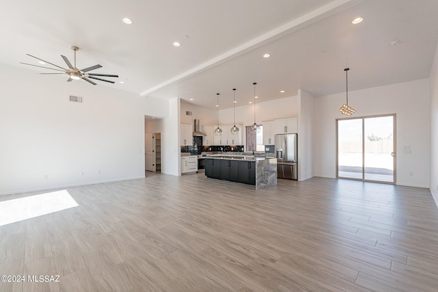 unfurnished living room with ceiling fan, light wood-type flooring, and beam ceiling