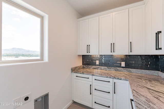 kitchen featuring white cabinets, light stone countertops, and tasteful backsplash