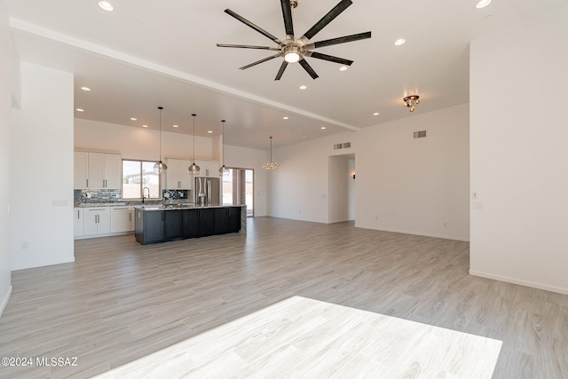 unfurnished living room featuring light wood-type flooring, sink, and ceiling fan