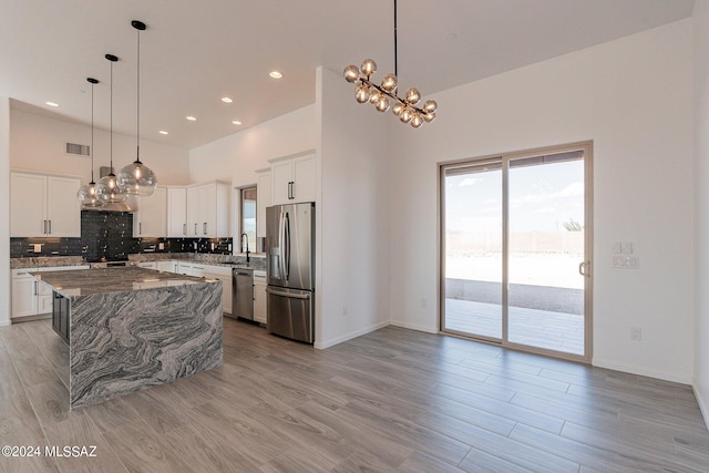 kitchen featuring a center island, stainless steel appliances, dark stone counters, and white cabinetry