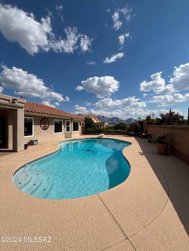 view of pool featuring a mountain view, a diving board, and a patio