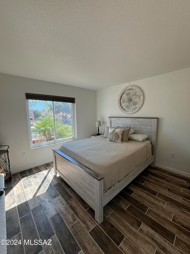 bedroom featuring dark wood-type flooring and a textured ceiling