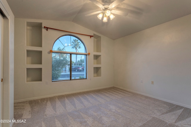 carpeted spare room featuring lofted ceiling, ceiling fan, and built in features