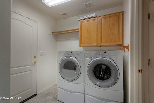 laundry room with washer and clothes dryer, light tile patterned floors, and cabinets