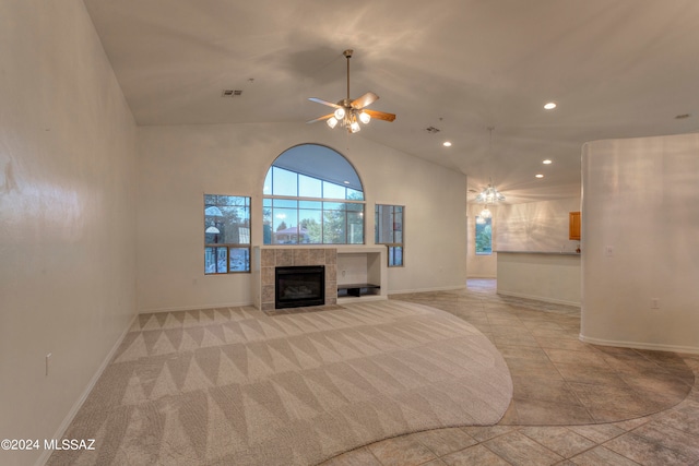 unfurnished living room featuring a tile fireplace, light tile patterned flooring, ceiling fan, and high vaulted ceiling