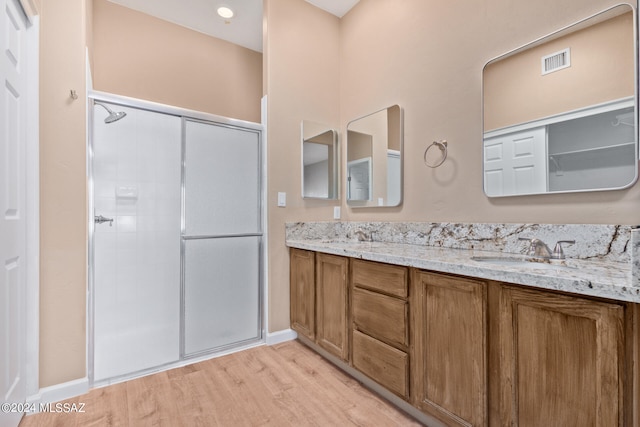 bathroom with a shower with shower door, wood-type flooring, and vanity