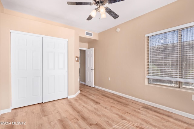 unfurnished bedroom featuring light wood-type flooring, ceiling fan, and a closet