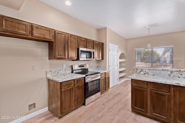 2521 S Pecan Valley Pl, Green Valley, AZ 85614 - kitchen featuring stainless steel appliances, hanging light fixtures, light wood-style floors, arched walkways, and light stone counters