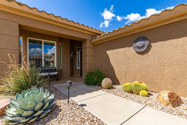 view of exterior entry featuring stucco siding and a tiled roof