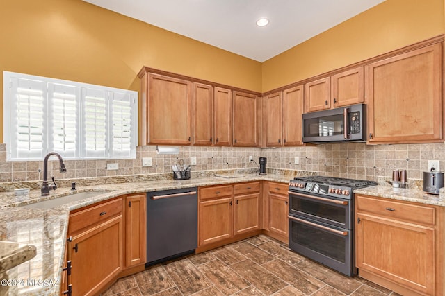 kitchen featuring stainless steel appliances, light stone countertops, decorative backsplash, and a sink