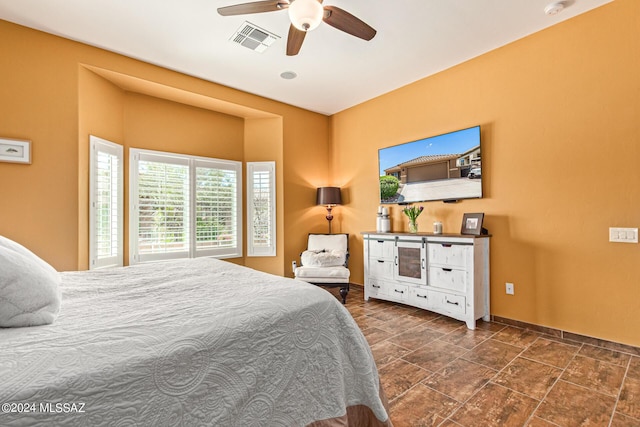 bedroom with baseboards, ceiling fan, stone finish floor, and visible vents