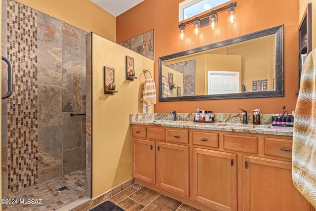 full bath with a sink, double vanity, and tiled shower