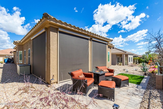 rear view of house featuring a tiled roof, a patio area, and stucco siding