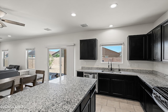 kitchen featuring light stone countertops, a sink, and dark cabinets