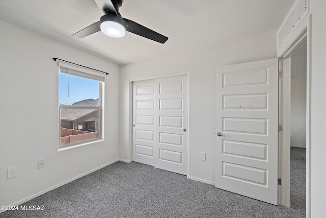 unfurnished bedroom with a ceiling fan, a closet, baseboards, and dark colored carpet