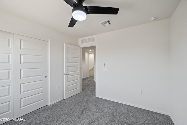 unfurnished bedroom featuring dark colored carpet, ceiling fan, and a closet