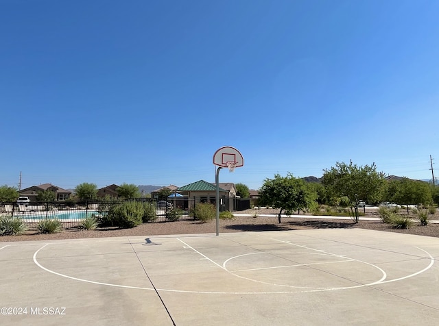 view of sport court with community basketball court, fence, and a fenced in pool