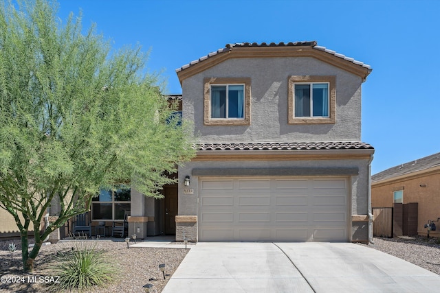 mediterranean / spanish house featuring stucco siding, a tile roof, a garage, and concrete driveway