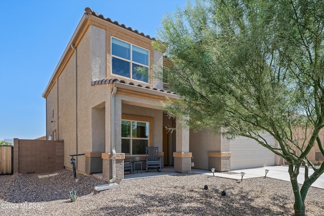 view of front facade featuring a tile roof, stucco siding, fence, and concrete driveway